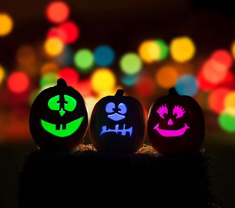 Three jack-o-lanterns with fluorescent light glowing from out of them.